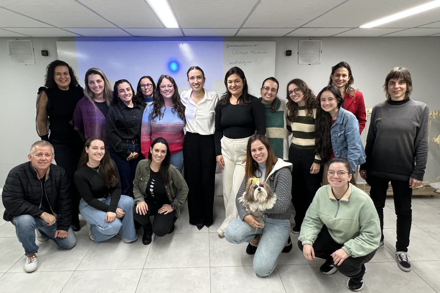Grupo de pessoas posicionado em duas fileiras, voltado para a câmera.
